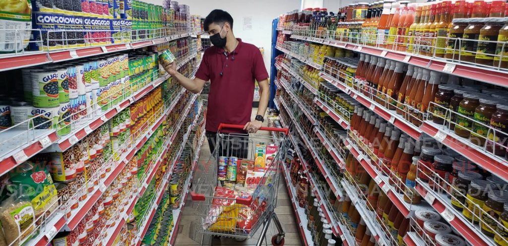  Rhaynnet Jimehez checks the price of a canned food product at supermarket in Port of Spain on Monday.  - PHOTO BY ROGER JACOB