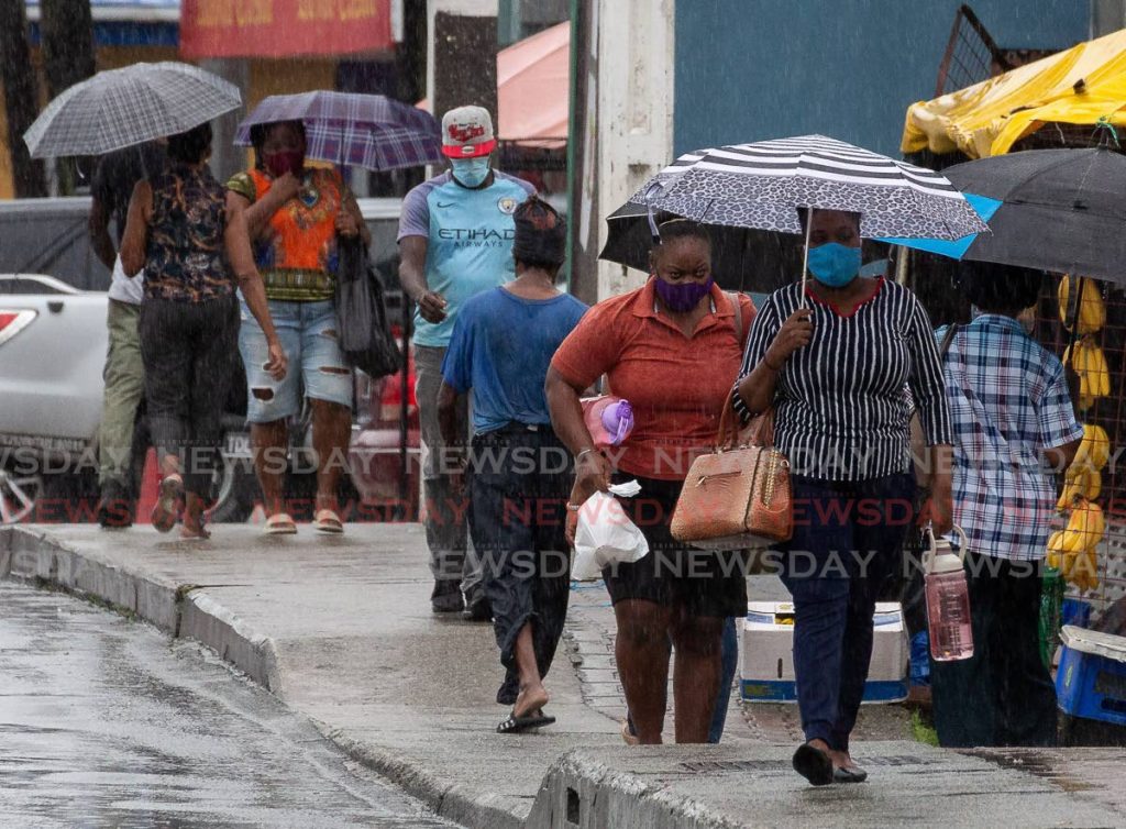 Pedestrians use umbrellas to shelter from the heavy rain on Friday while some walked through unbothered along Carrington Street, Scarborough. - David Reid