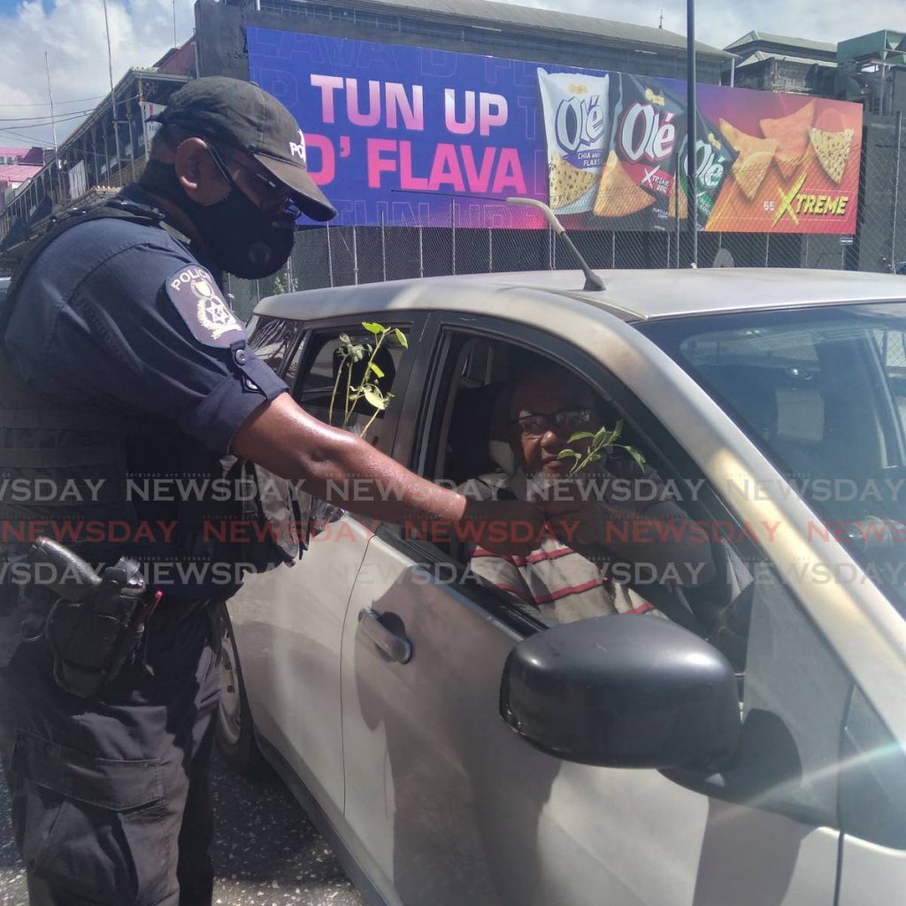 Cpl Mohan of the Central Police Station, left, gives a plant to a driver on Frederick Street, Port of Spain on Saturday morning. 
The initiative which was led by Insp Ramesh Soodeen seeks to encourage citizens to take an interest in agriculture while strengthening ties with the community.  - Photo by Shane Superville