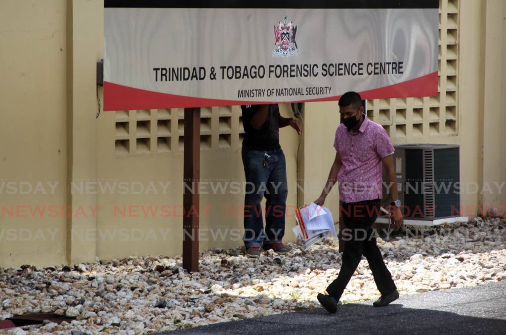 In this file photo, an investigator carries evidence samples to the Forensic Science Centre, St James. - 
