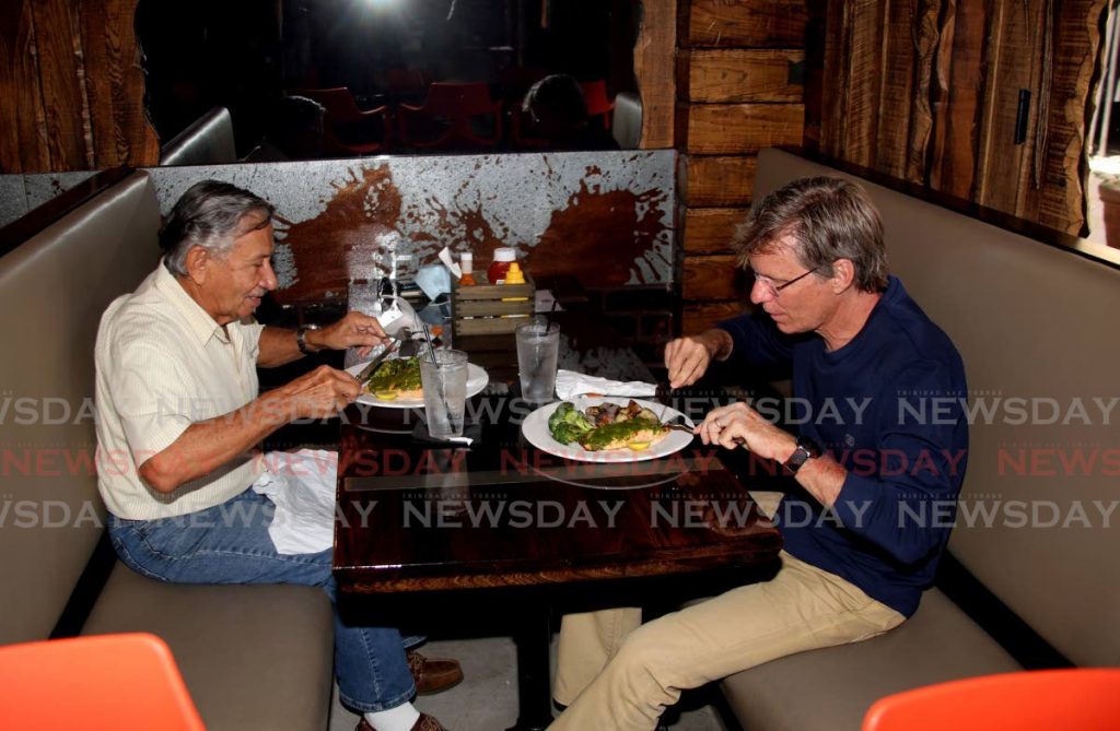 Silbourne Clarke, left, and James Potter have lunch at Tommy's Pub at MovieTowne Port of Spain. - SUREASH CHOLAI