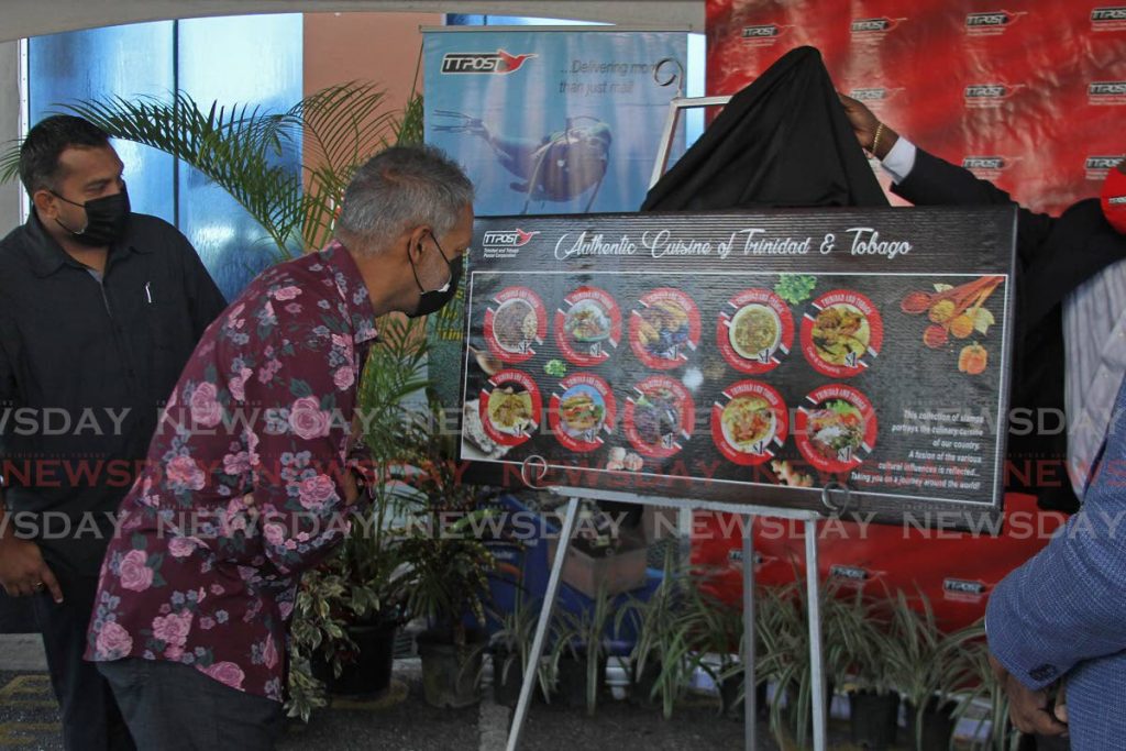 Agriculture Minister Clarence Rambharat looks, alongside minister in the  Ministry of Agriculture, Land and Fisheries Avinash Singh, at the display of TTPost stamps featuring local dishes launched in Chaguanas on Saturday. - Photo by Marvin Hamilton