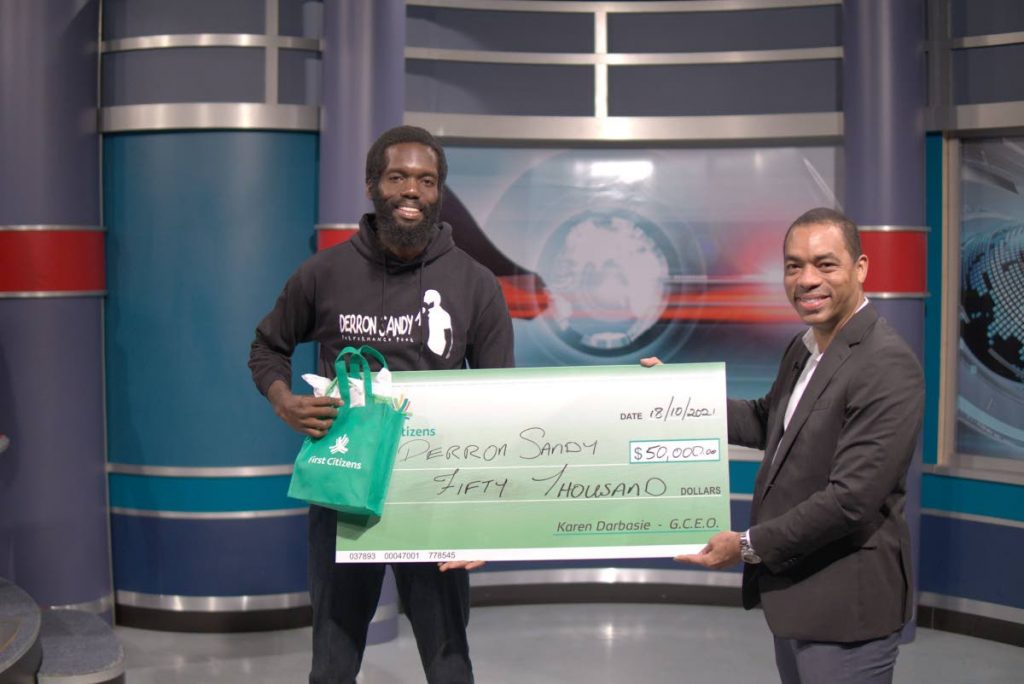 Grand Slam 2021 winner Derron Sandy is presented with his prize of $50,000 from Jason Julien, group deputy chief executive officer - business generation, First Citizens, on the NOW Morning Show on TTT on October 18. - 