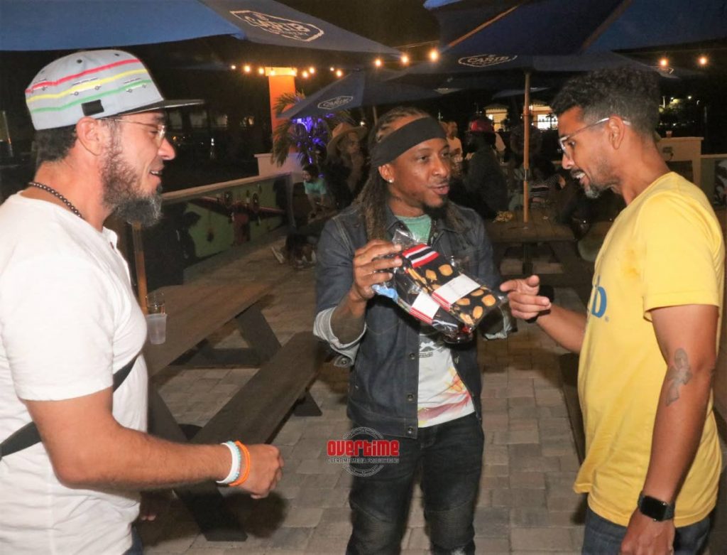  Kerwin Du Bois shows off two pairs of Ktreadz Caribbean Socks to Carib Brewery USA marketing director, Asa P Sealy,  right, as Ktreadz  founder Kamal Laird, left, looks on following the launch of the new Can You Feel It video featuring Du Bois, alongside Jamaican talent Shenseea