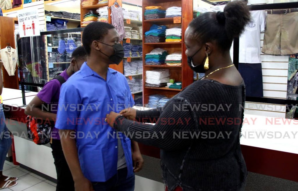 Jaylan Jones checks, at Bradford's on Henry Street, Port of Spain, the fit of a school shirt for her son Tyrelle who returns to classes at Tranquillity Secondary School on Monday. - PHOTO BY SUREASH CHOLAI
