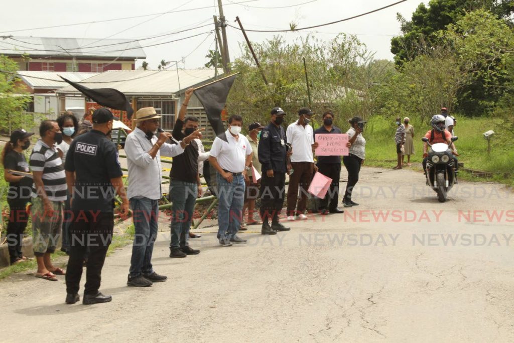 Two policemen monitor a roadside protest by San Francique residents on Saturday. Fyzabad MP Lackram Bodoe, fourth from left, was among the protesters. - Photo by Marvin Hamilton