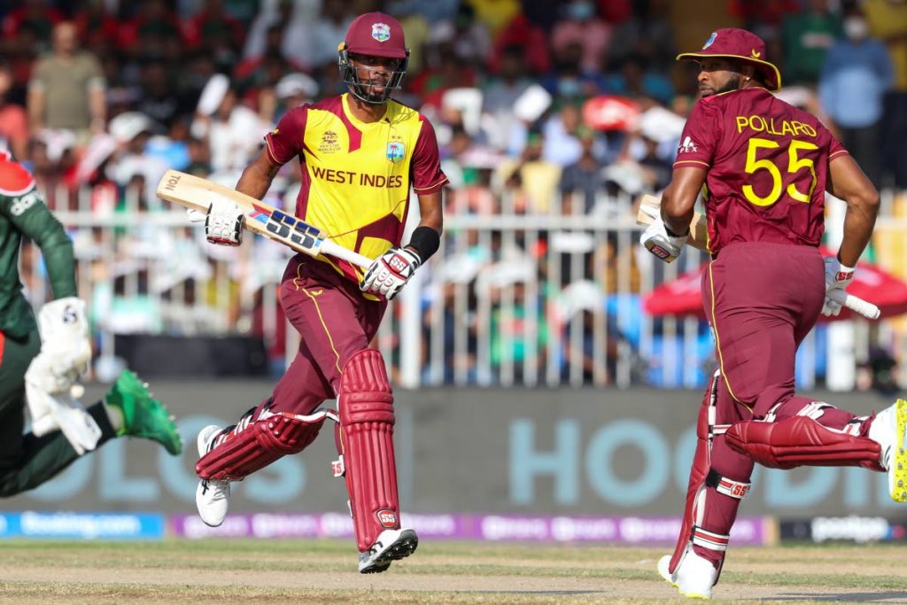 West Indies' Roston Chase, left, and Kieron Pollard run between the wickets during the Cricket Twenty20 World Cup match between the West Windies and Bangladesh in Sharjah, UAE, Friday, Oct. 29, 2021. (AP Photo) 