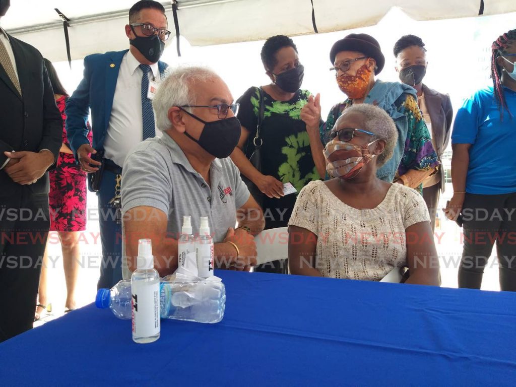Health Minister Terrence Deyalsingh chats with Ste Madeleine resident Angela Cayenne as she waits to get a blood pressure test on Friday at  the launch of the 2021 National Care Fair at the Southern Academy for the Performing Arts. - Tyrell Gittens
