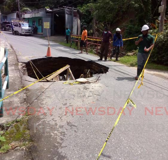 Workers assess damage caused by the caving in of the road outside Cascadia Hotel, St Ann's, on Friday.  - 