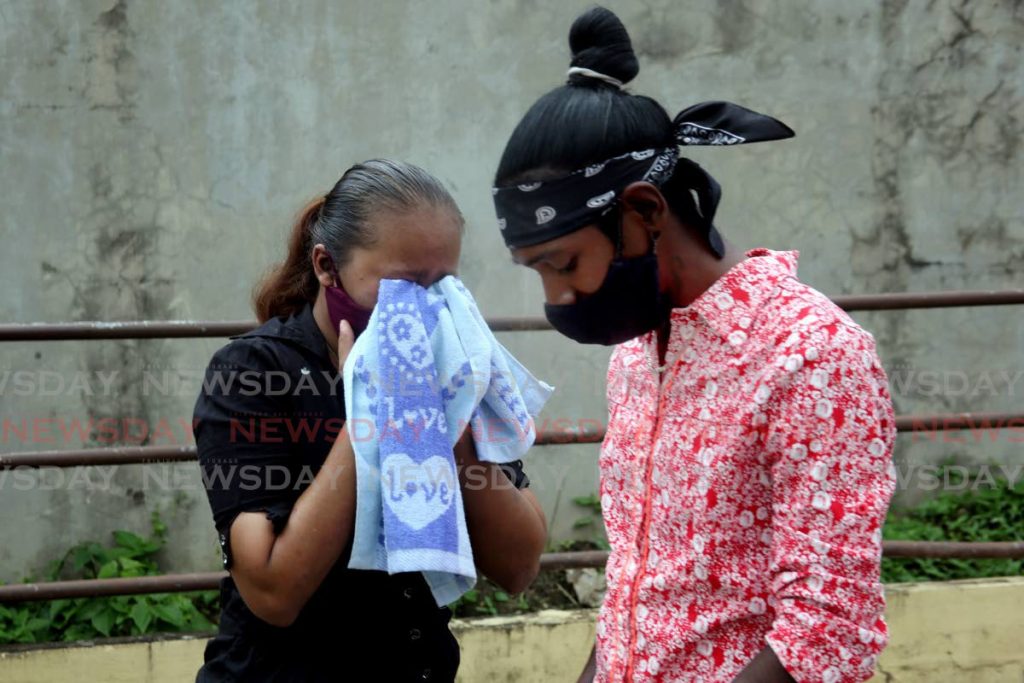 The son of murdered security guard Kimraj Jaggassar, Neemi Jaggassar, alongside weeping common-law wife Sherice Ragoonanan outside the Forensic Science Centre, St James on Friday. - PHOTO BY SUREASH CHOLAI