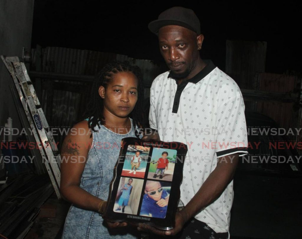 Crystal Paponette and Andre Richardson, the parents of Yasin Richardson, hold  a plaque with photos of their children at their home. - Ayanna Kinsale