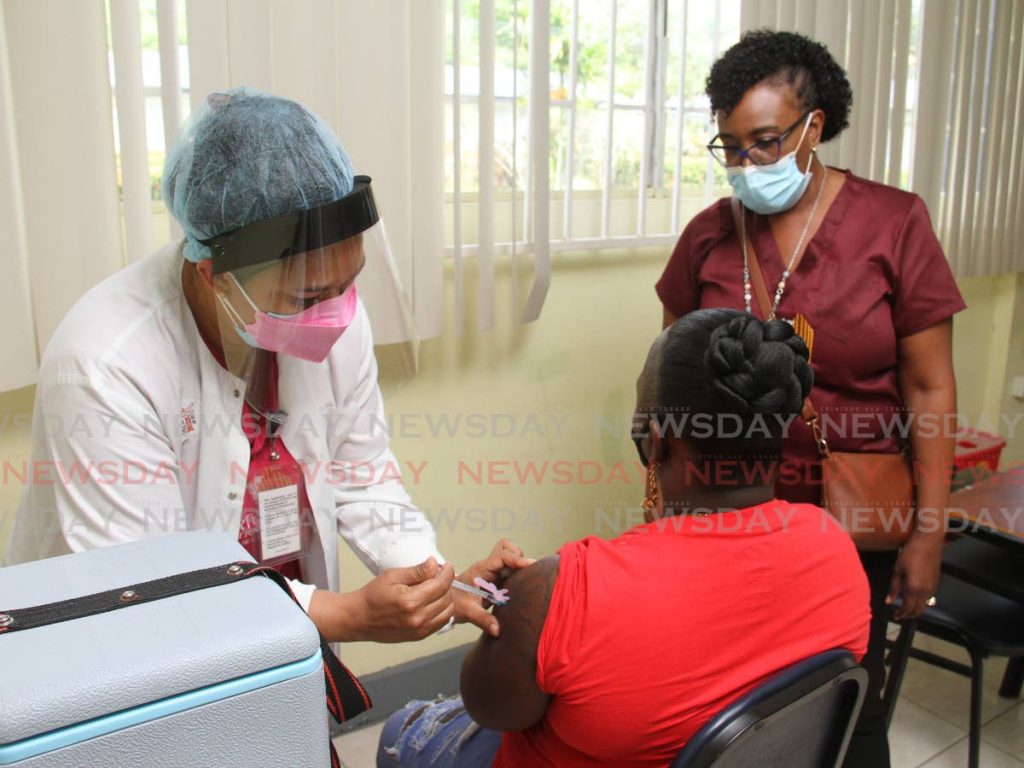Nurse Yamisleydi Gomez gives Teneisha Wilson a dose of the Pfizer vaccine at Costatt, El Dorado campus on October 29 as district health visitor Helena Peters looks on. File photo/Angelo Marcelle