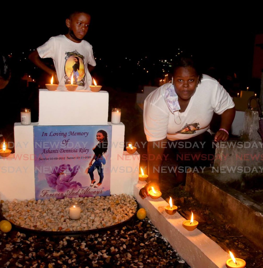 Candice Riley, mother of murdered teenager Ashanti Riley, lights deyas and candles at her daughter's gravesite at the San Juan Cemetery on All Souls Day, while her son Jonathan looks on. Photo by Sureash Cholai - 