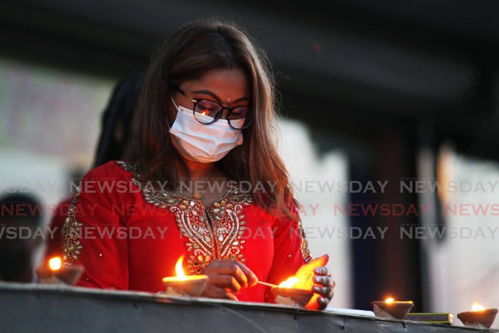In this November 2021 Anita Persad light deyas outside RRM Plaza, High Street, San Fernando as part of their Divali celebrations. Photo by Lincoln Holder