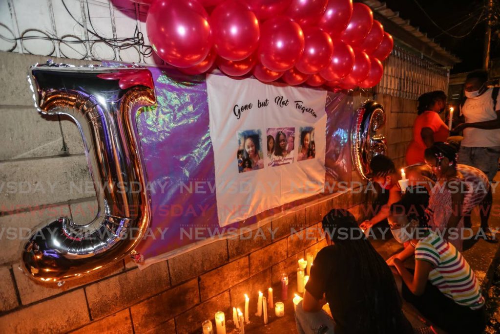 Family and friends light candles for murder victim Kezia Jeneka Guerra in Cantaro Village, Santa Cruz on Saturday. - Photo by Jeff Mayers