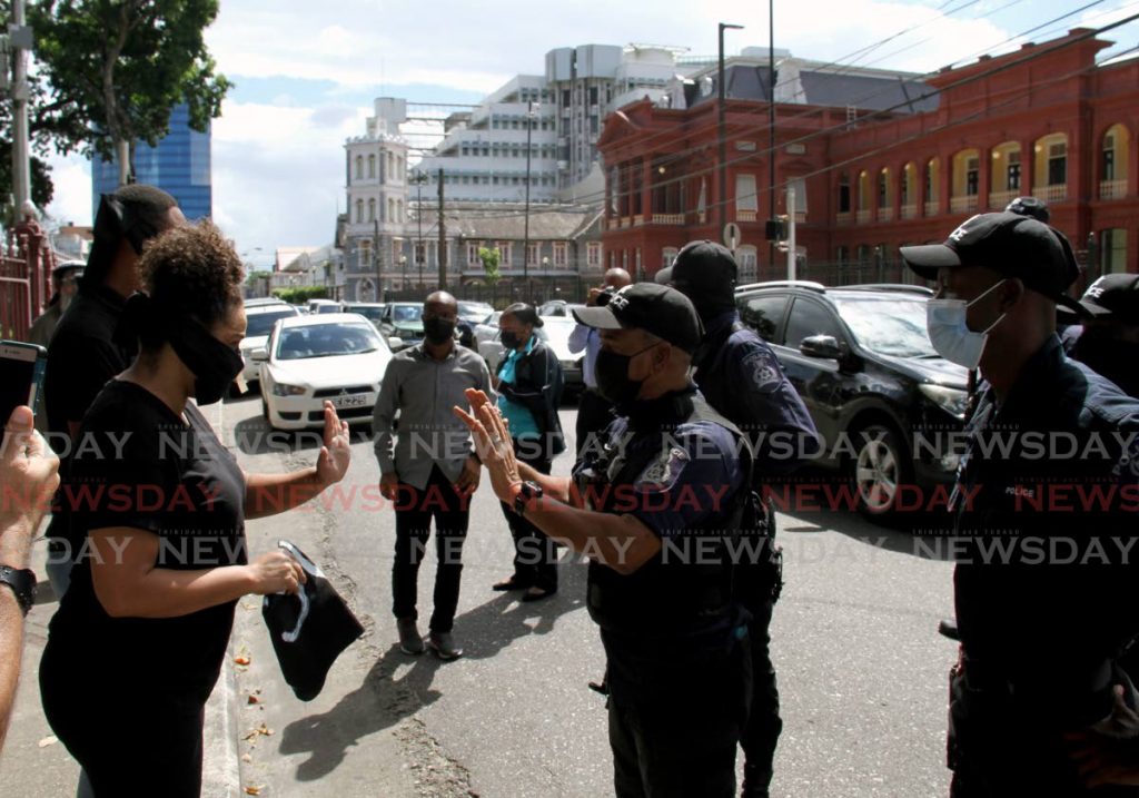 A police officer cautions activist Marsha Riley-Walker during a demonstration outside the Red House on Abercromby Street. - AYANNA KINSALE