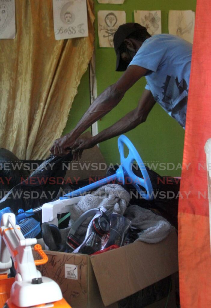 A man removes the belongings of Shaquille Primus from his home on Celestine Drive, Pelican Ext, Morvant on Tuesday. Primus was killed on Monday night.  - Angelo Marcelle