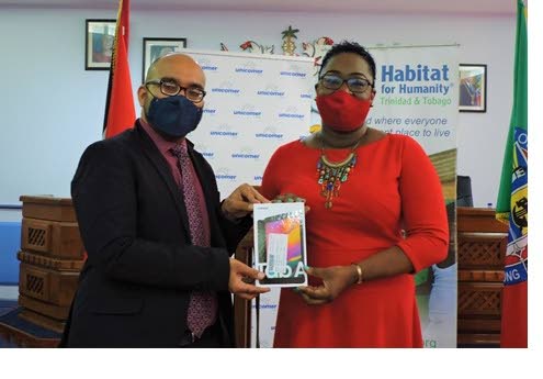 Shahad Ali, PRO, Unicomer (Trinidad) Ltd presents a tablet to a successful participant in a PASSA training programme facilitated by Habitat for Humanity TT.
 - courtesy Port of Spain City Corporation