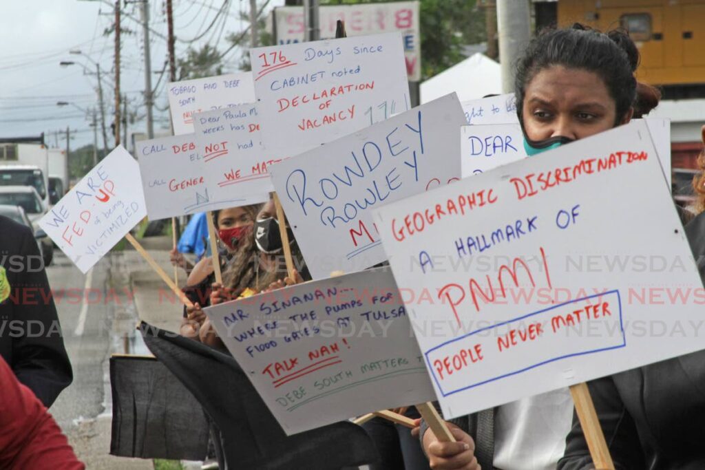 Debe South residents hold up placards as they demand a by-election be held for the vacant local government seat in their district during a protest outside the Penal/Debe Regional Corporation on Friday. - Marvin Hamilton