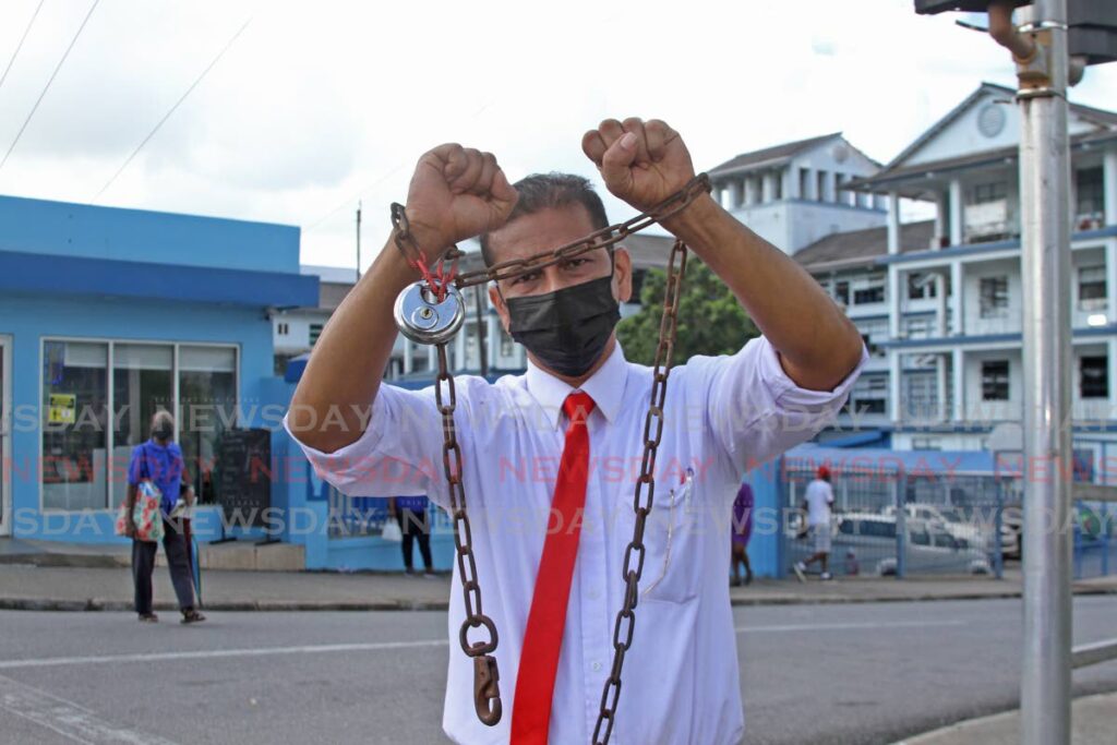 A chain is wrapped around and secured with a lock on the hands of Ricardo Goolcharan, a ward manager at the San Fernando General Hospital, who had a peaceful demonstration on Monday morning outside the hospital.  Photo by Marvin Hamilton