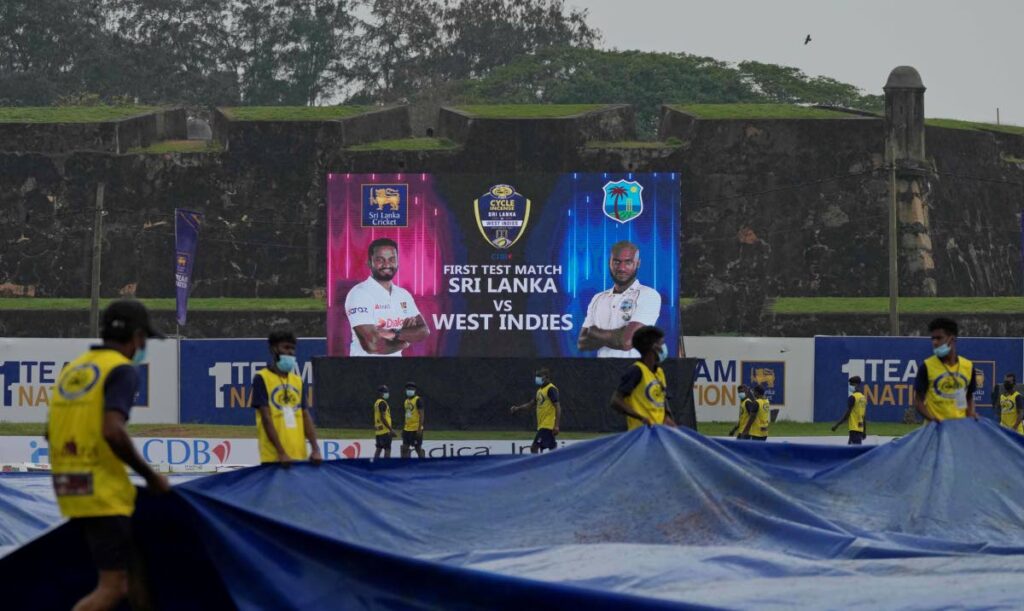 Sri Lankan ground staff brings in covers as it rains during the third day of the first Test between Sri Lanka and West Indies in Sri Lanka in Galle, Sri Lanka, on Tuesday. (AP PHOTO) 