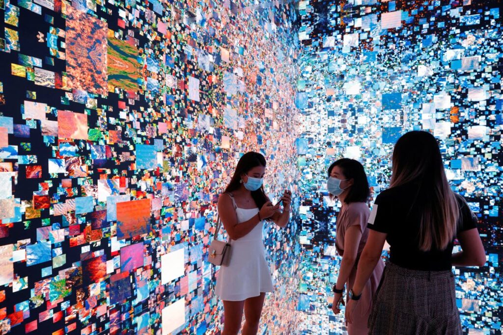 In this photo taken on September 30, Visitors take photos in front of an immersive art installation titled 'Machine Hallucinations — Space: Metaverse' by media artist Refik Anadol, which was to be converted into NFT and auctioned online at Sotheby's, at the Digital Art Fair, in Hong Kong, China. Photo taken from mnews.world - 