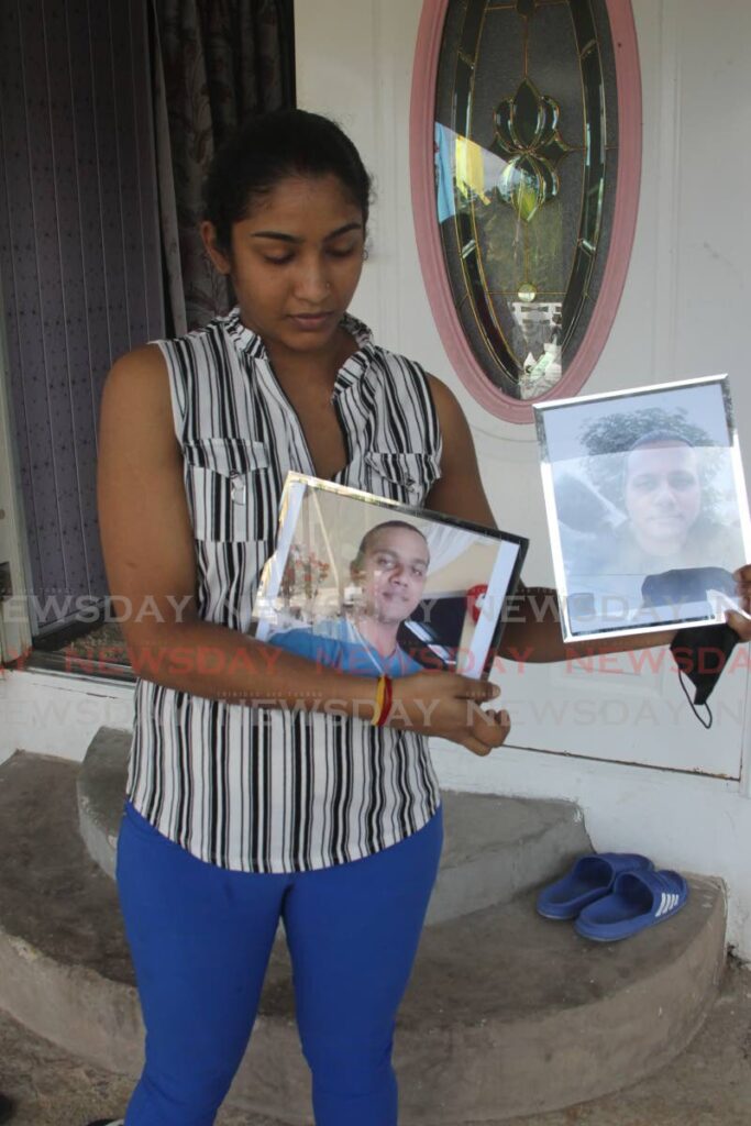 ALL I HAVE LEFT: Vicky Nanack holds framed photos of her husband Hansraj outside the family home in Cumuto on Wednesday. PHOTO BY ROGER JACOB - 
