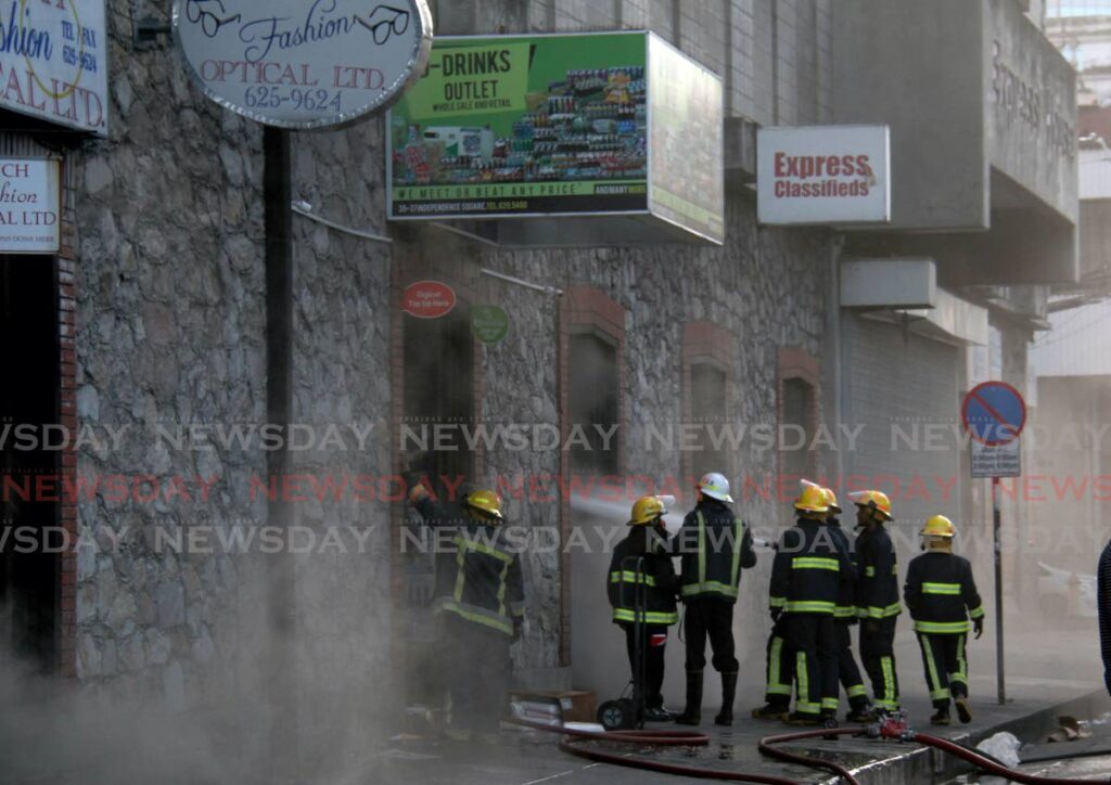 Firefighters attempt to put out a fire at D-Drinks Outlet at Express House building, Independence Square, Port of Spain on Sunday. - AYANNA KINSALE
