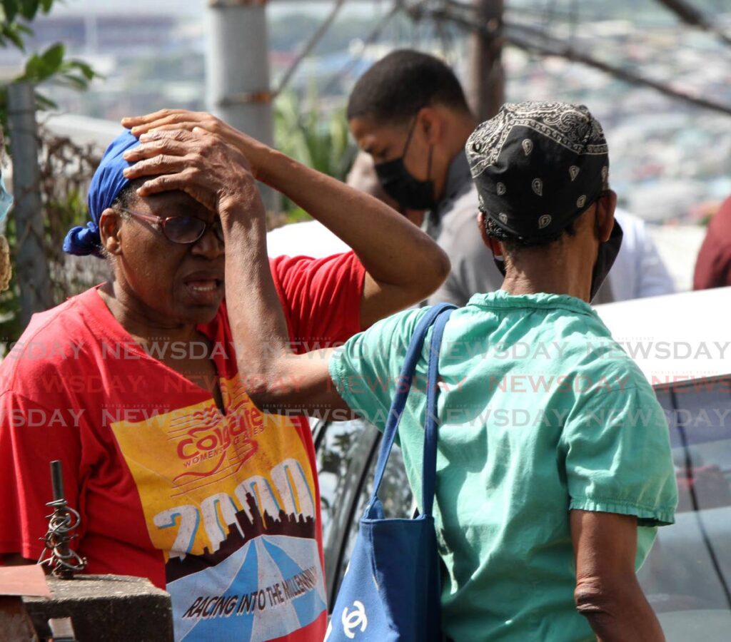 A woman is comforted after learning that two men were murdered in a house on Desperlie Crescent, Laventille,  on Monday. - Angelo Marcelle