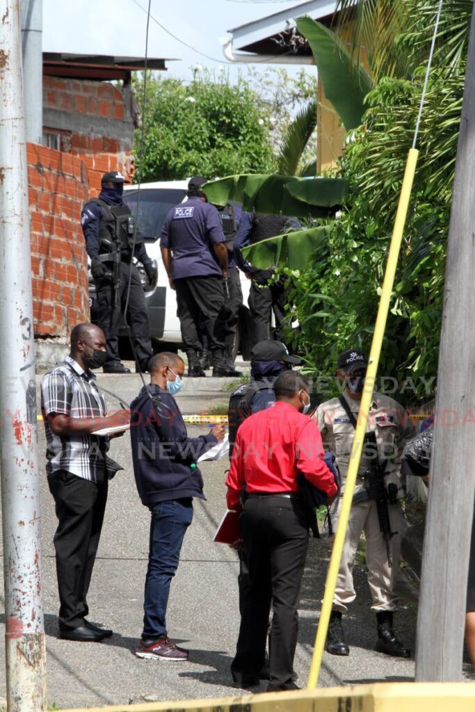 Police officers conduct their investigation into the murders on Despers Avenue, Laventille on Monday. - Photo by Angelo Marcelle