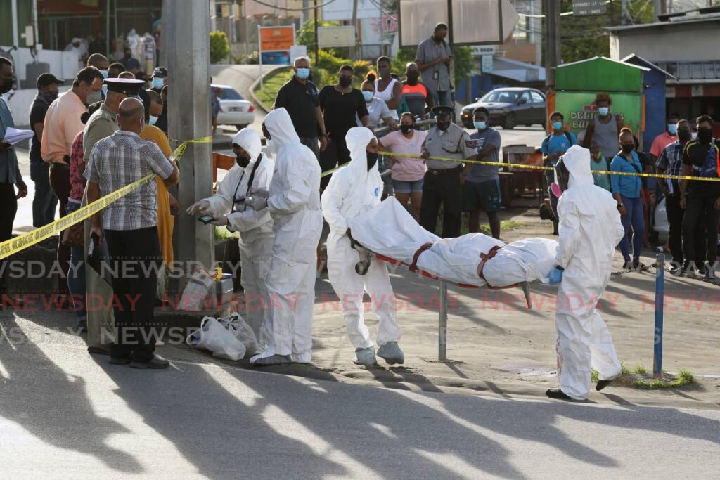 Undertakers remove the body of prisons officer Nigel Jones who was shot and killed while waiting for a taxi on the corner of Siparia Old Road and High Street, Siparia, on Monday.  - Lincoln Holder