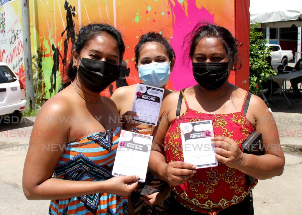 In this Ocotber 6, 2021 file photo, from left, sisters Nicole and Christine Beharry and their mother Audra display their vaccination cards after receiving the AstraZeneca vaccine at the Paddock, Queen's Park Savannah, Port of Spain. On Monday, the Ministry of Health rolls out the booster shots for people fully vaccinated with AstraZeneca, Sinopharm and Johnson and Johnson vaccines. - 