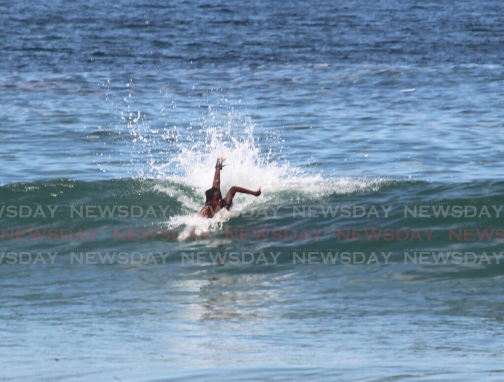 A man rides a surf board in Sans Souci on the east coast off Trinidad. Beaches reopen on Monday from 5 am to noon. - File photo/Roger Jacob