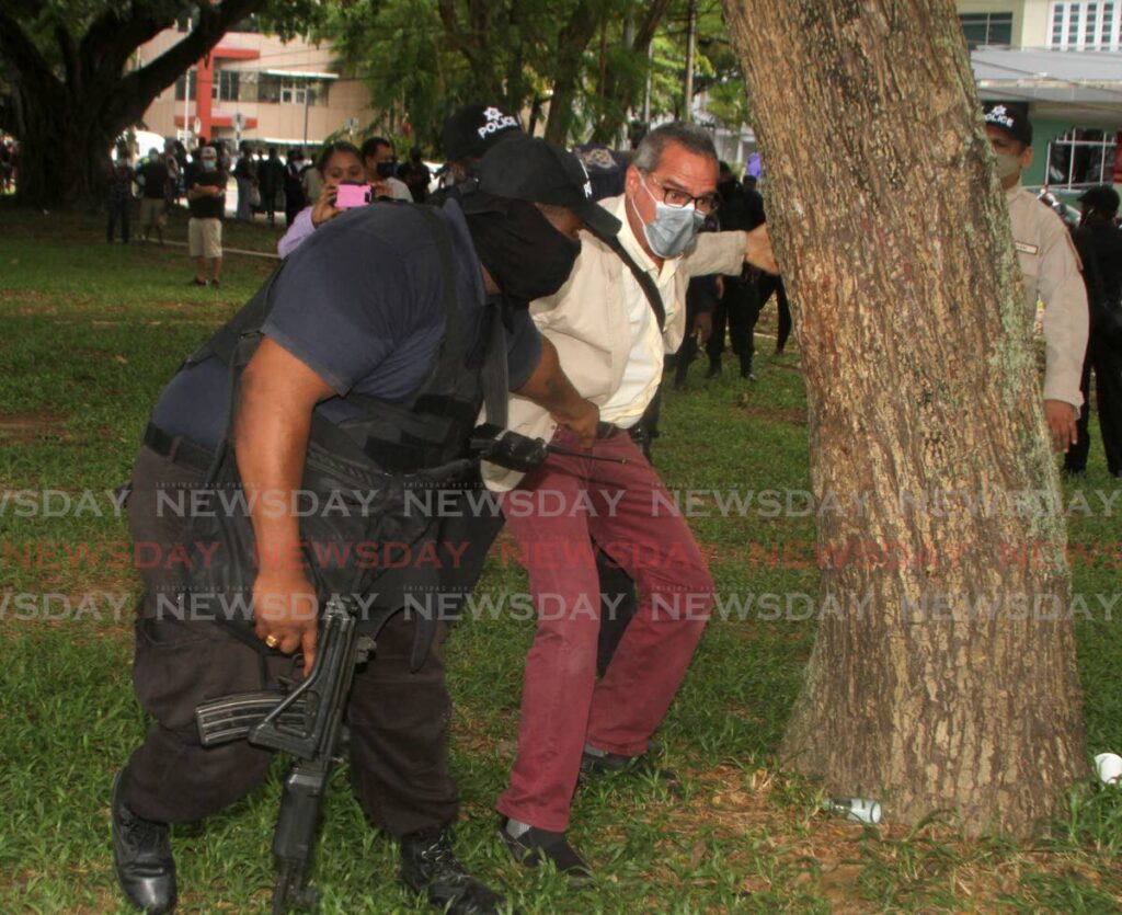 Fishermen and Friends of the Sea President Gary Aboud, hugs a tree as police try to arrest him at a protest at the Queen's Park Savannah, Port of Spain, Tuesday. - Photo by Angelo Marcelle