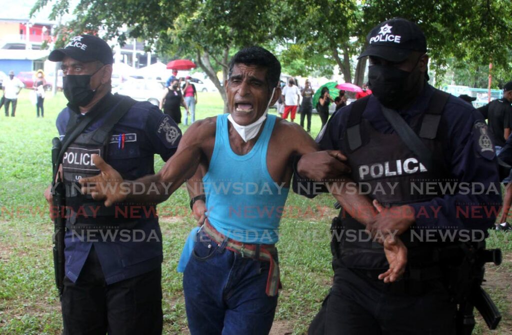 A man pleads his case to be released as police arrest him at a protest at the Queen's Park Savannah on Tuesday. - Angelo Marcelle