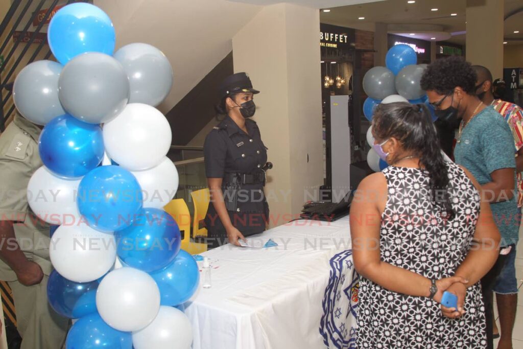 Members of the Princes Town municipal police on Tuesday at C3 Centre, Corinth interact with members of the public, where they distributed flyers and spoke to customers about safety tips for the Christmas season. - Lincoln Holder