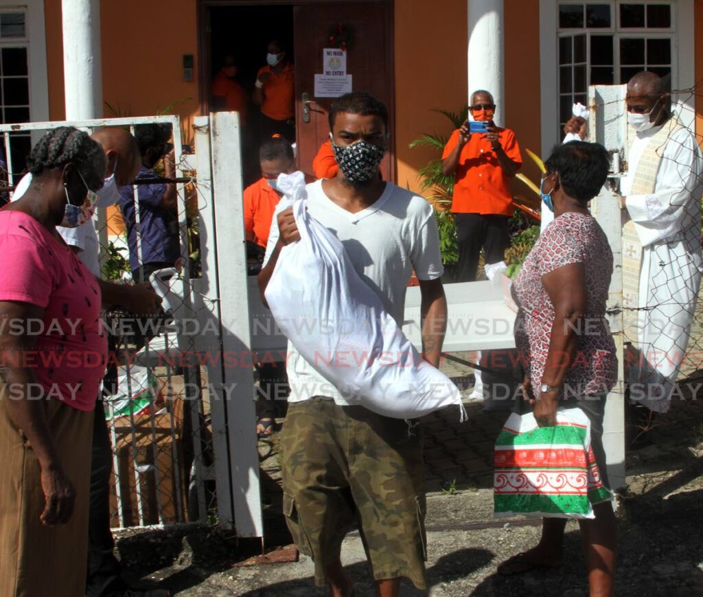 Residents of Mausica Lands, also known as Jones Town, take away food items from the People of Praise Food Bank and Life Centre, De Gannes Street, Arima, during its launch on Friday. - Angelo Marcelle
