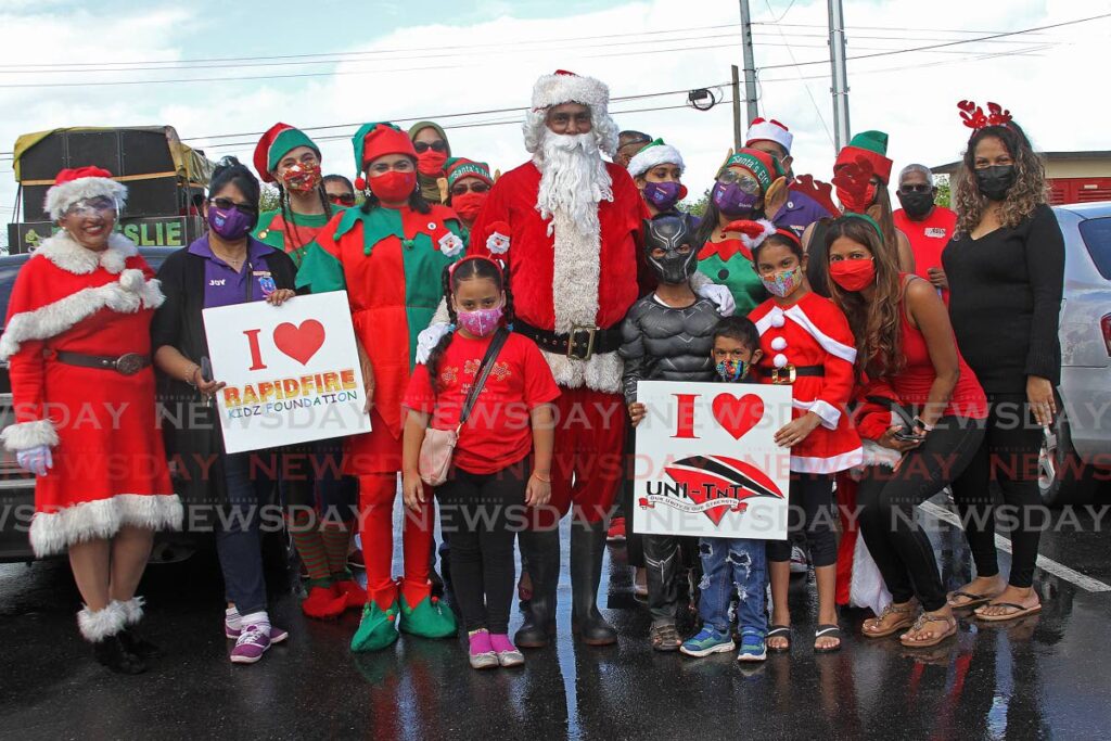 Kevin Ratiram, attorney and founder of NGO Rapidfire Kidz Foundation, dressed as Santa, poses with some of the children and his helpers during a toy drive at Reform Village on Saturday. - Marvin Hamilton