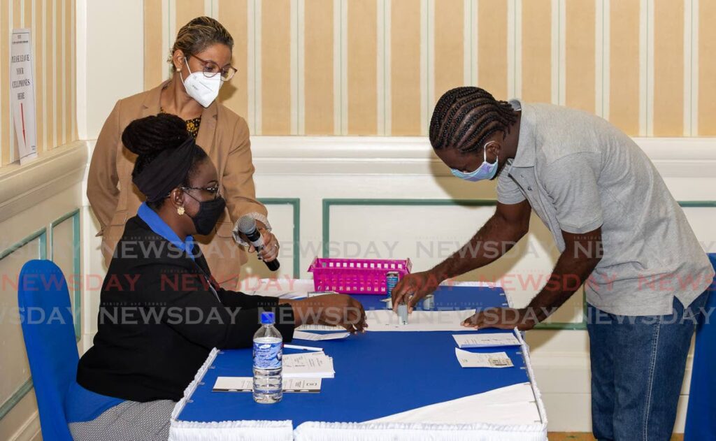  The deputy presiding officer, left, shows Ajay Alleyne, right, how to stamp his ballot paper correctly at the EBC’s mock voting process at Magdalena Resort and Spa last Saturday ahead of the THA election on Monday. - Photo by David Reid