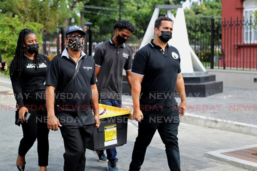 Randolph Bharatt (left), father of Andrea Bharatt, and social activist Phillip Edward Alexander are assisted by volunteers with delivering signed petitions to the Parliament in Port of Spain on Tuesday. - ROGER JACOB