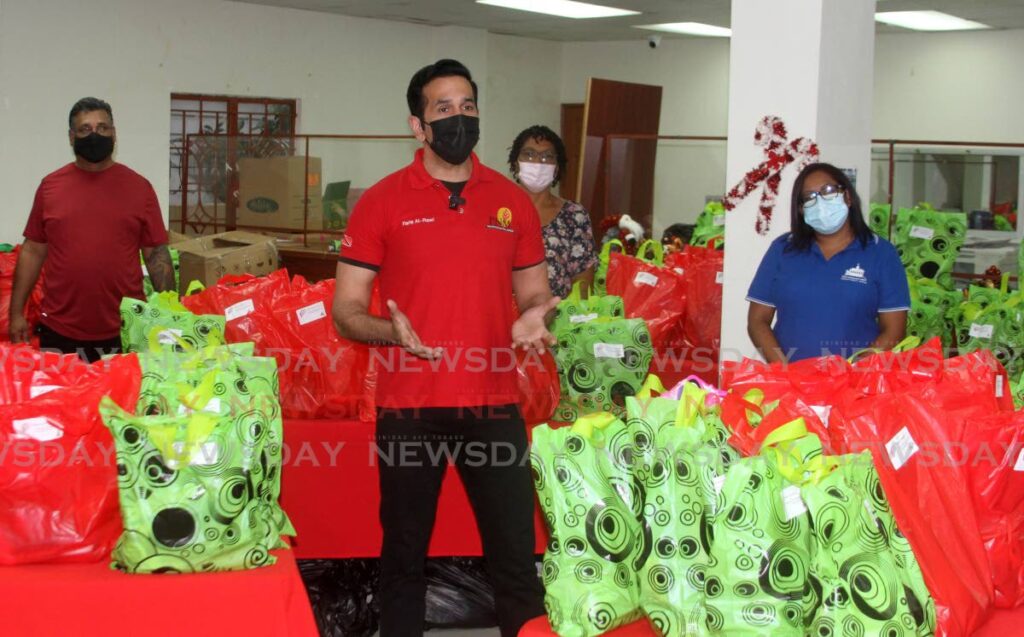 Attorney General and San Fernando West MP Faris Al-Rawi, along with his staff, stand among hundreds of bags filled with Christmas gifts for children at his constituency office for their annual toy distribution, at Independence Avenue, San Fernando on Saturday.  PHOTO BY ANGELO MARCELLE 