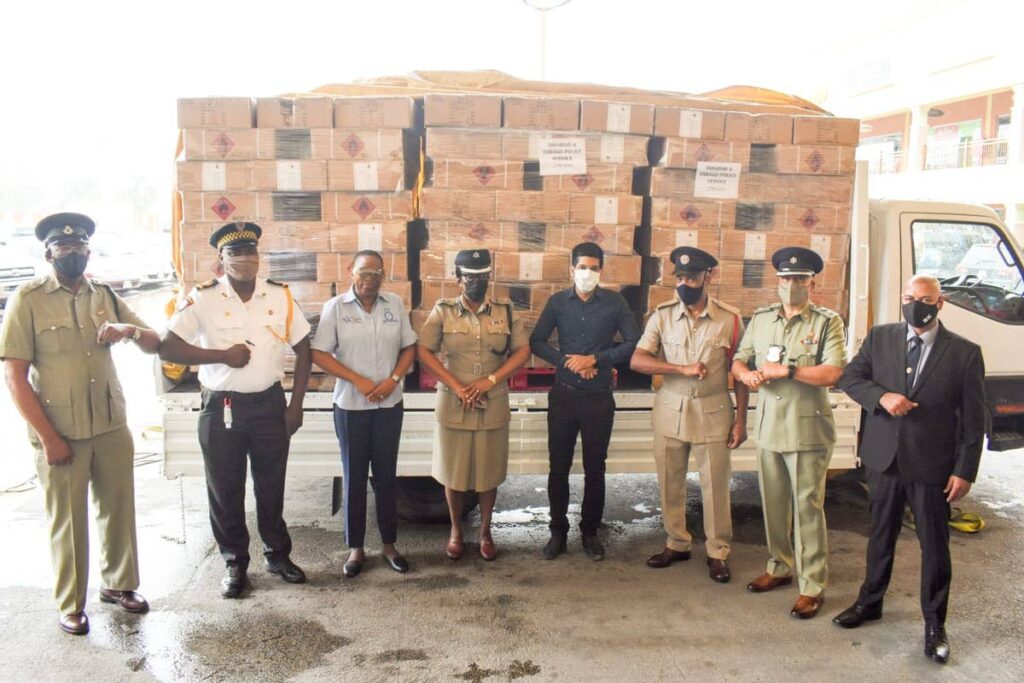 Representatives of the different bodies making up the protective services stand near the truck loaded with boxes containing 21,600 bottles of hand sanitisers donated by Pennywise Cosmetics Ltd on Tuesday. PHOTO COURTESY PENNYWISE COSMETICS LTD - Pennywise