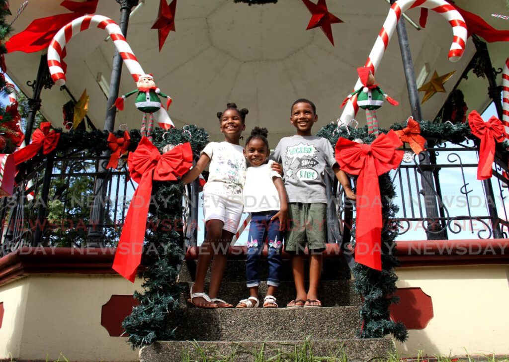 Siblings Jadiya, Aniya and Matius Mc Donald smile for a photo at the decorated gazebo at Woodford Sqaure, Port of Spain on Thursday. - AYANNA KINSALE