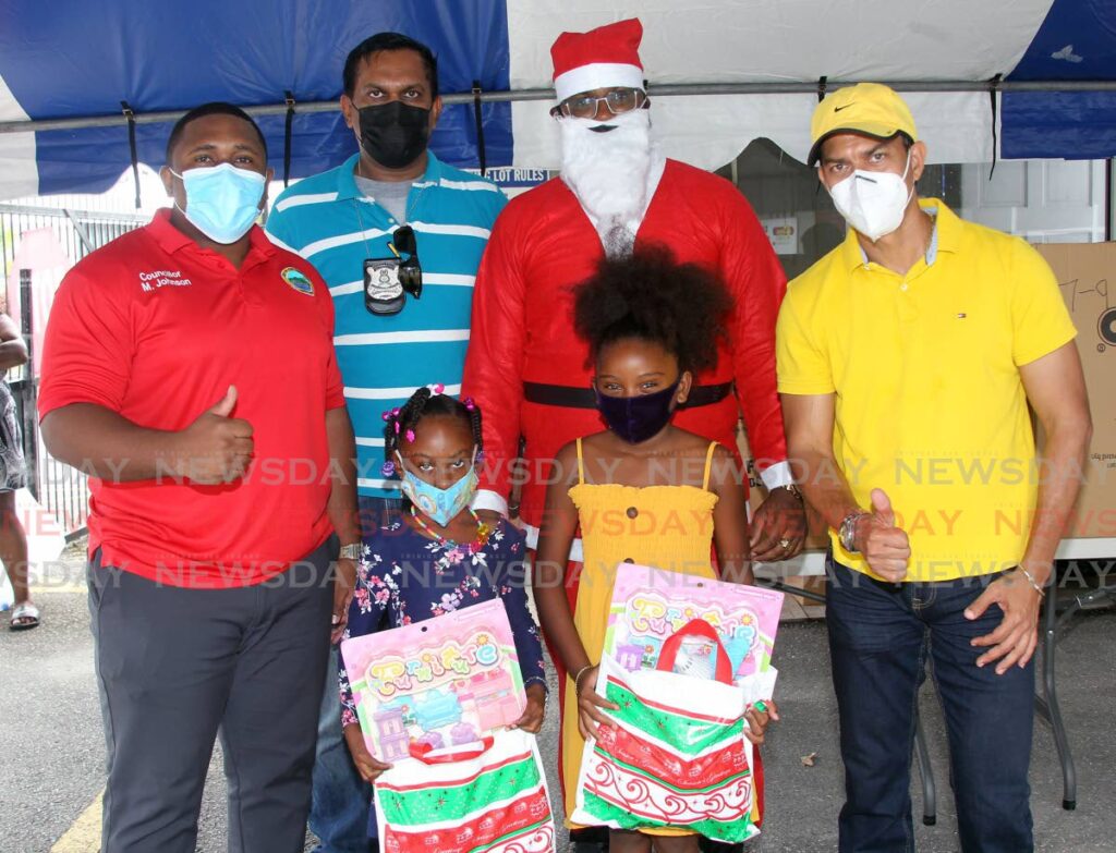 From Left: PNM councillor for Marabella west Michael Johnson with Insp Ronald Ramlogan, Santa (PC Figaro) and UNC councillor for Marabella south / Vistabella Marcus Girdharie as they present Christmas gifts to children during the Marabella police toy drive held FENS Marabelal compound on Sunday - Photo by Lincoln Holder