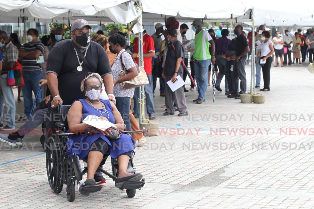 People wait to be registered  to get their vaccine booster at the SAPA mass vaccination site in San Fernando on Monday. - Photo by Lincoln Holder  