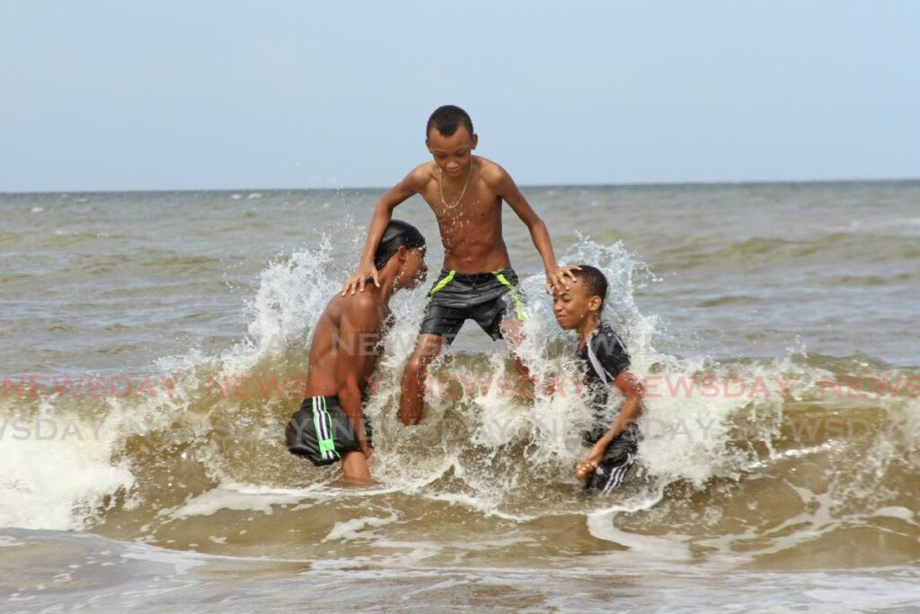 HAVING FUN: Three boys having fun at Clifton Hill Beach in Point Fortin, on Monday morning. Photo by Marvin Hamilton
