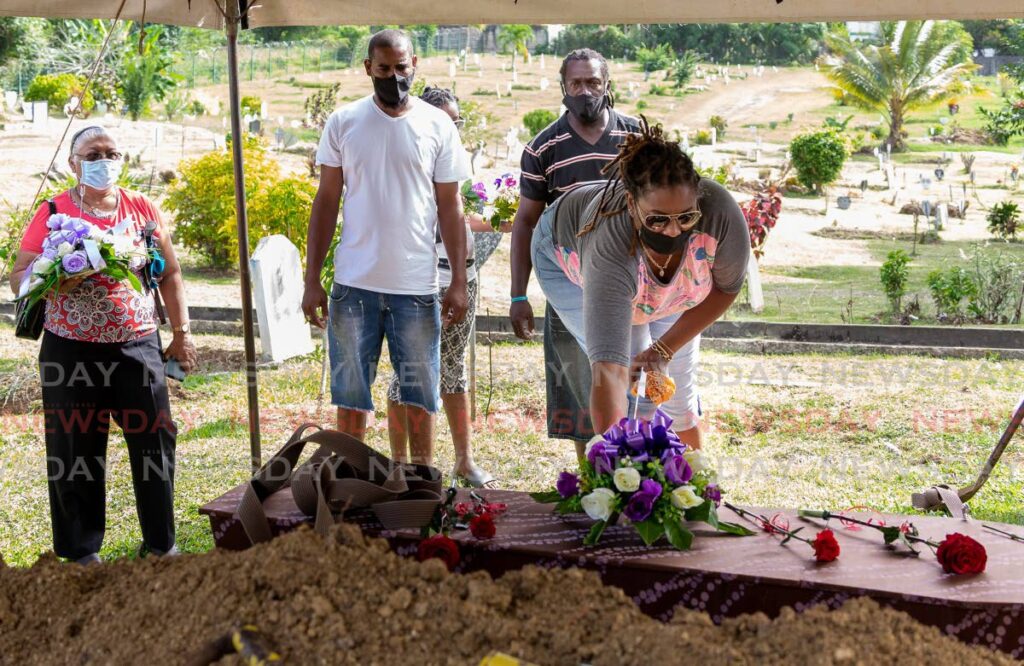 Patrisha Ramsumair Cromarthy lays flowers on the casket carrying her mother Narupa Ramsumair, at the Buccoo public cemetery on Tuesday. - Photo by David Reid