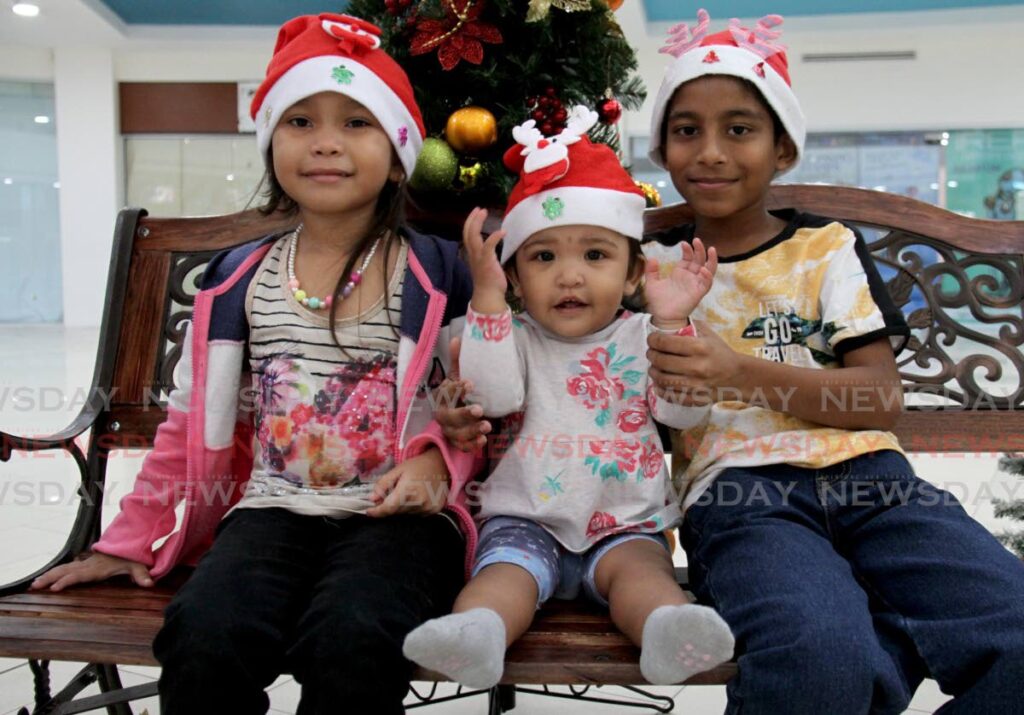 Siblings Josmary Salazar, 5, Arya Rampersad, 1, and Dylan Rampersad 9, all smiles as they enjoy their visit to Trincity Shopping Mall on Tuesday. Photo by Ayanna Kinsale