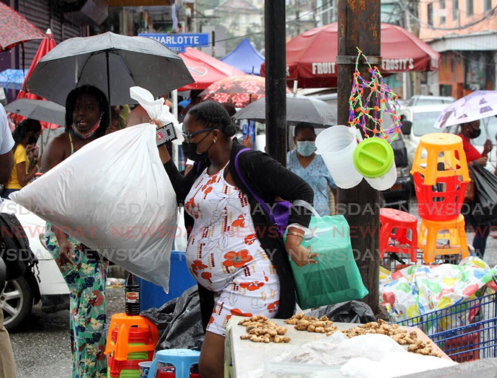 The rain didn't stop this shopper from getting her items on Wednesday in Port of Spain. - Angelo Marcelle
