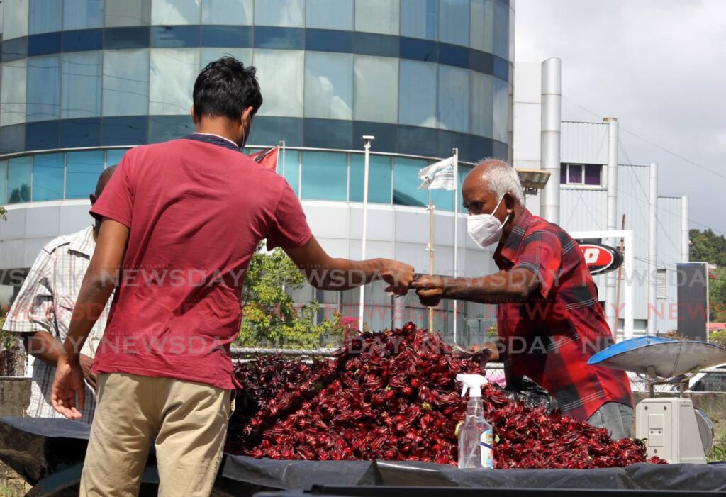 A customer buys sorrel from a vendor at the roundabout near Maritime Plaza, Barataria on Thursday. - ROGER JACOB